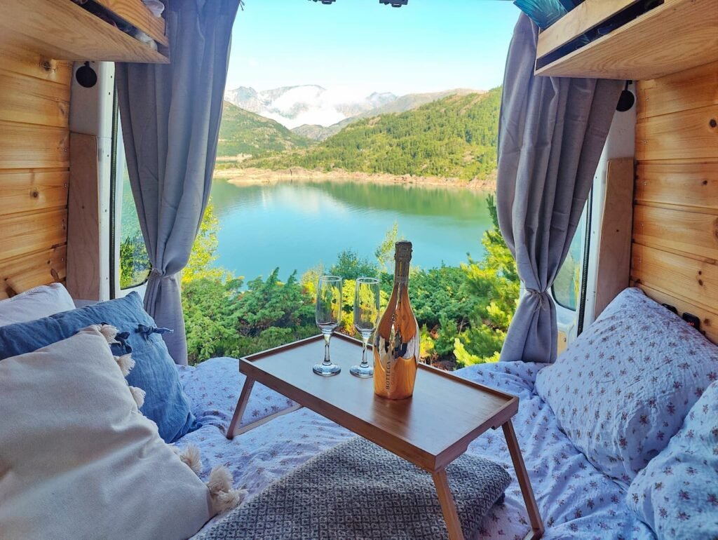 View from the bed inside a Cabin Campers campervan overlooking a Norwegian lake and mountains.